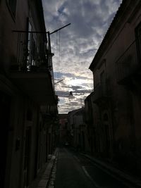 Street amidst buildings against sky at dusk