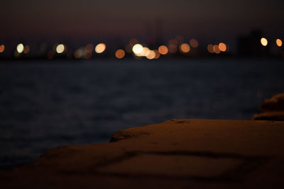 Illuminated lights on beach against sky at night