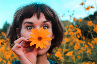 Close-up of young woman with flower on field