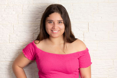 Portrait of young woman standing against wall