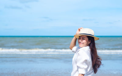 Young woman wearing hat while standing on beach