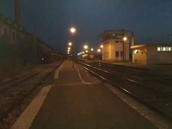 Empty road along illuminated buildings at night