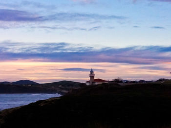 Lighthouse by sea against sky