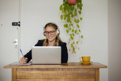 Woman working at home with laptop and papers on desk and headphones. home office . gray notebook 