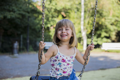 Happy girl enjoying on swing at park