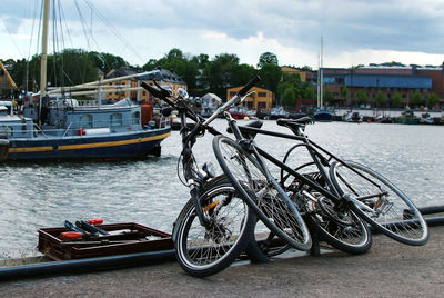 Bicycles on river in city against sky