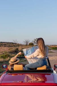 Rear view of woman sitting on boat against clear sky
