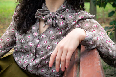 Midsection of woman with hands hair sitting outdoors