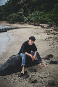 Full length of young man sitting on rock