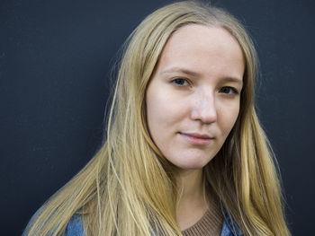 Portrait of young woman with blond hair against gray background