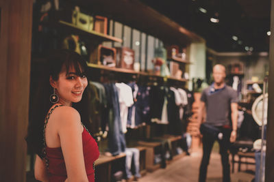 Portrait of young woman standing in clothing store
