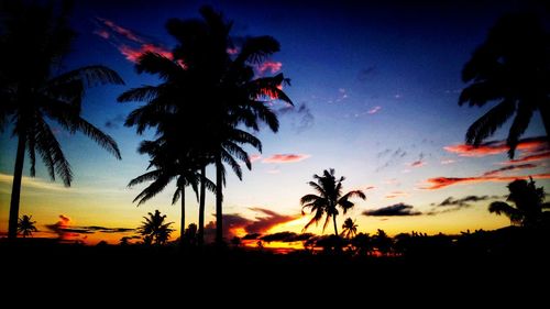 Silhouette palm trees against romantic sky at sunset