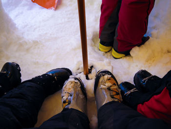 Looking down at a group of mountaineering boot clad feet in the snow inside a cook tent