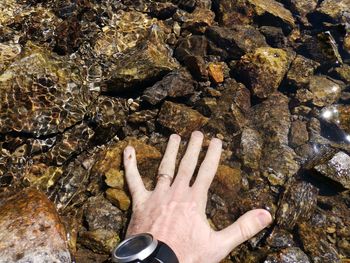 High angle view of hand over rocks in sea