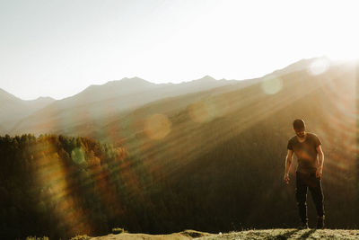 Rear view of man standing on mountain against sky