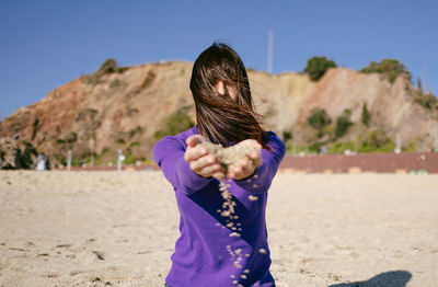 Mature woman playing with the sand on a sunny winter day at the beach