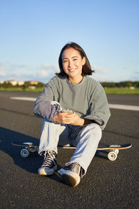 Portrait of young woman sitting on road