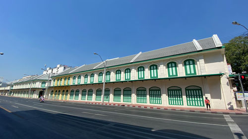 Building by road against clear blue sky