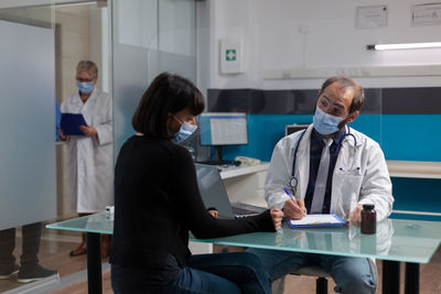 Doctor wearing mask examining patient in clinic