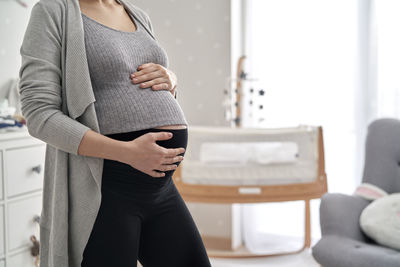 Midsection of pregnant woman standing at home