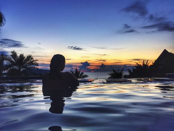 Silhouette woman in swimming pool during sunset