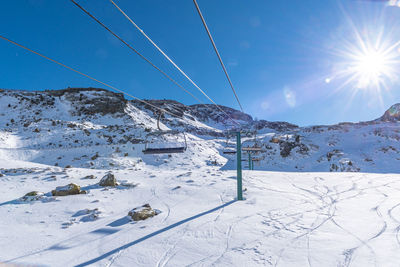 Scenic view of snow covered mountains against bright sun