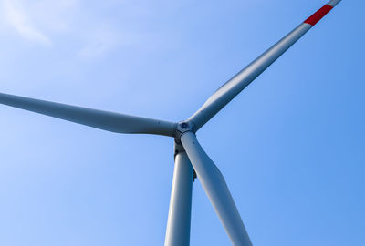 Low angle view of wind turbine against blue sky