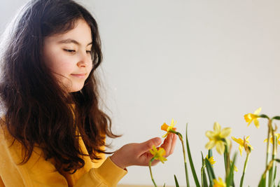 Portrait of dark haired girl touching daffodil flowers