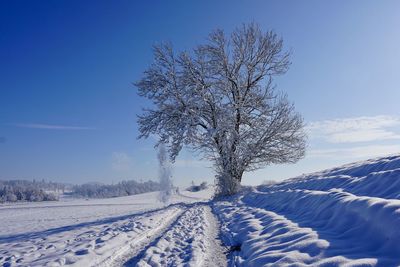 Snow covered landscape against clear blue sky