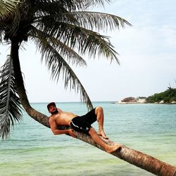 Full length of shirtless man in sea against sky