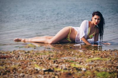 Portrait of seductive woman lying at sea shore