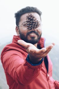 Close-up of young man throwing pine cone into the air