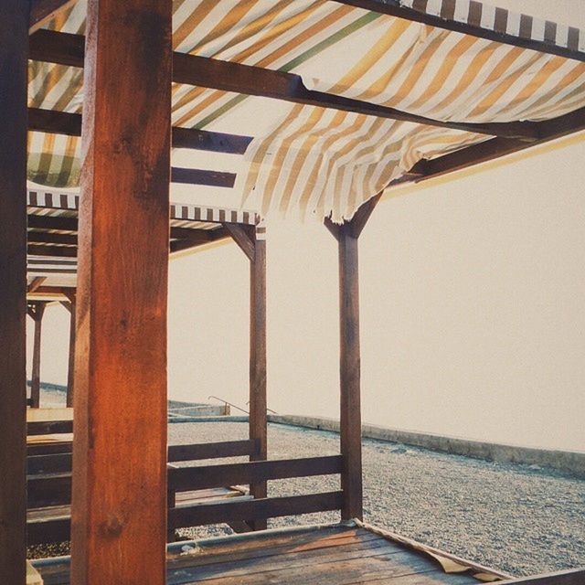 sea, water, built structure, beach, wood - material, clear sky, pier, railing, architecture, sunlight, sand, horizon over water, no people, nature, tranquility, day, wooden, outdoors, shore, tranquil scene