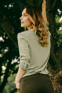 Low angle view of beautiful woman standing by tree