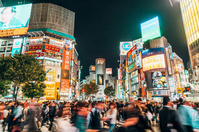 People walking on illuminated street in city at night