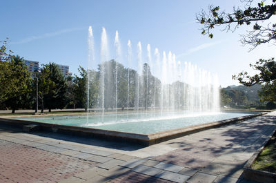 Fountain by swimming pool against sky