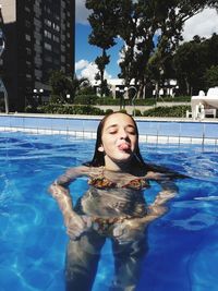 Girl sticking out tongue in swimming pool