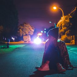 Man against illuminated lights and sky at night