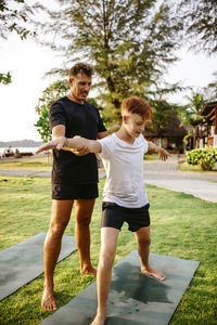 Father teaching warrior position to son in park during vacation