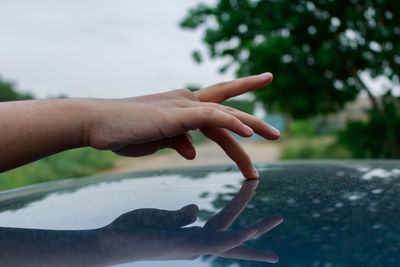 Close-up of human hand touching reflective surface