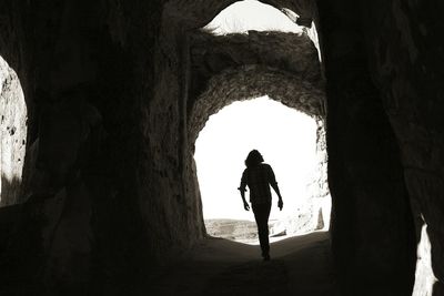 Silhouette man walking in cave