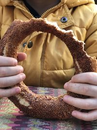 Midsection of boy holding bread on table while sitting at restaurant outdoors