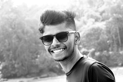 Portrait of young man wearing sunglasses against trees