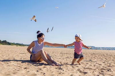 Mother and son sitting on the beach and flying around the birds seagulls