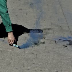 Cropped hand of man holding distress flare on footpath