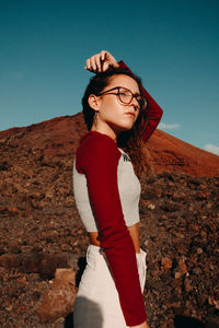 Full length of smiling young woman standing against sky