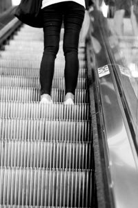 Low section of woman standing on escalator