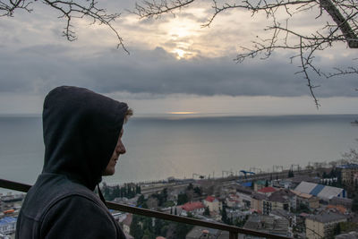 Man looking at city by sea against sky