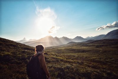 Rear view of woman standing on mountain against sky