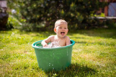 Cute baby girl playing in bucket at lawn